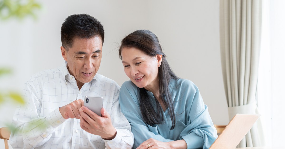 スマートフォンで旅行の予約内容を確かめる夫婦