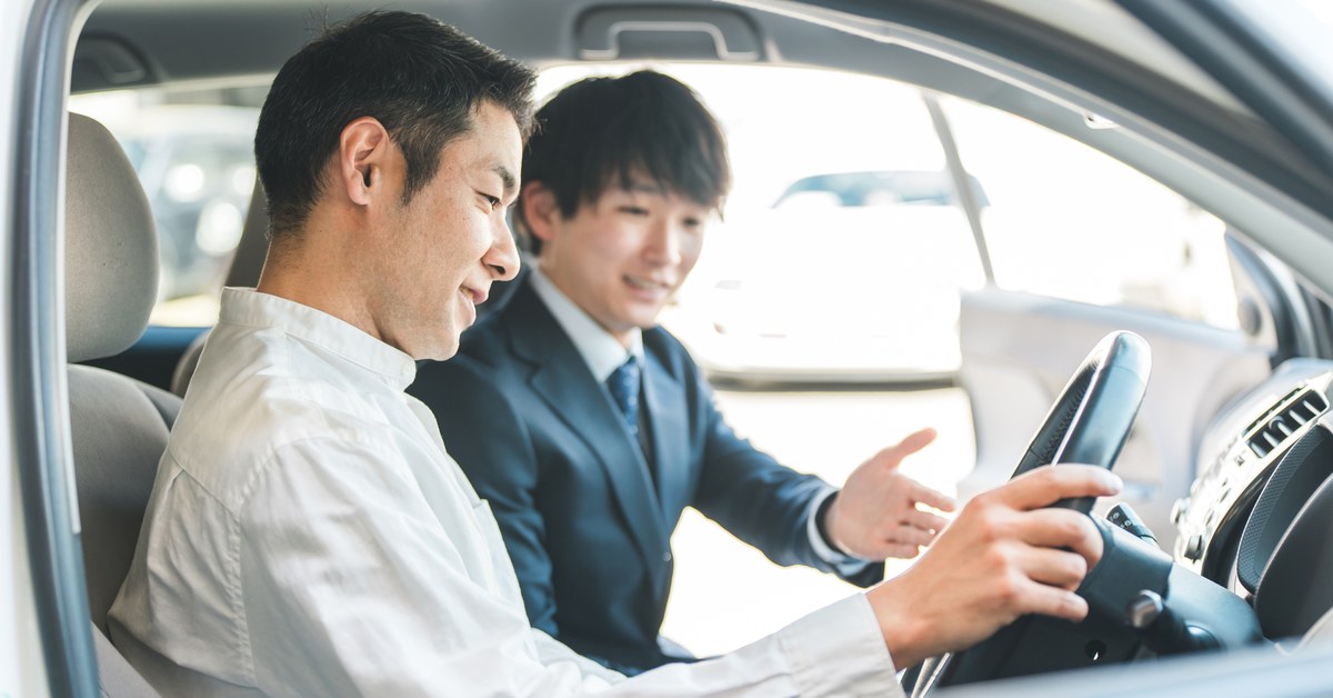 車の中で販売担当者から説明を受ける客