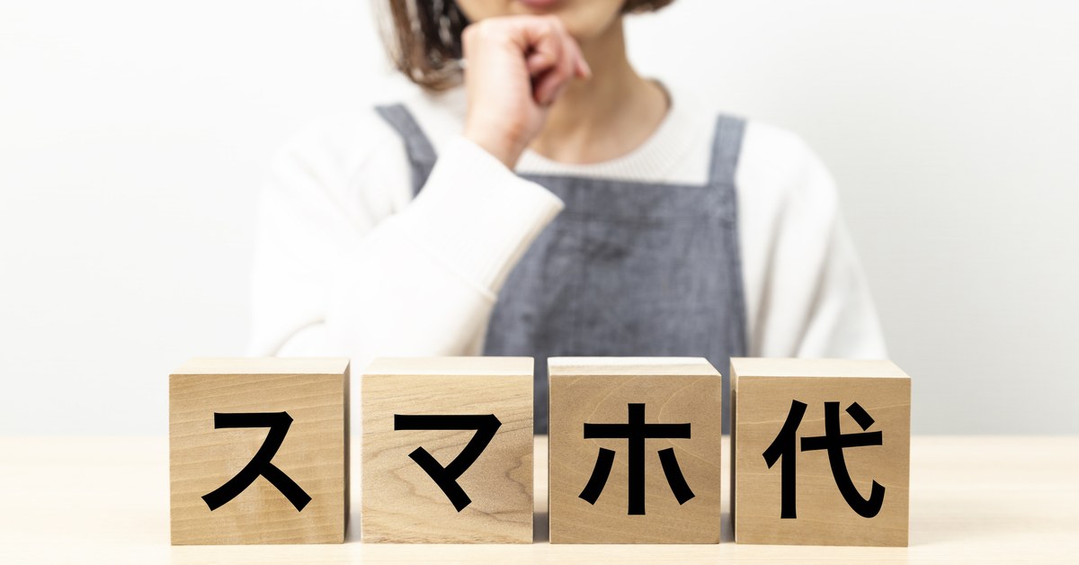 「スマホ代」と書かれた木製ブロックの前で考える女性