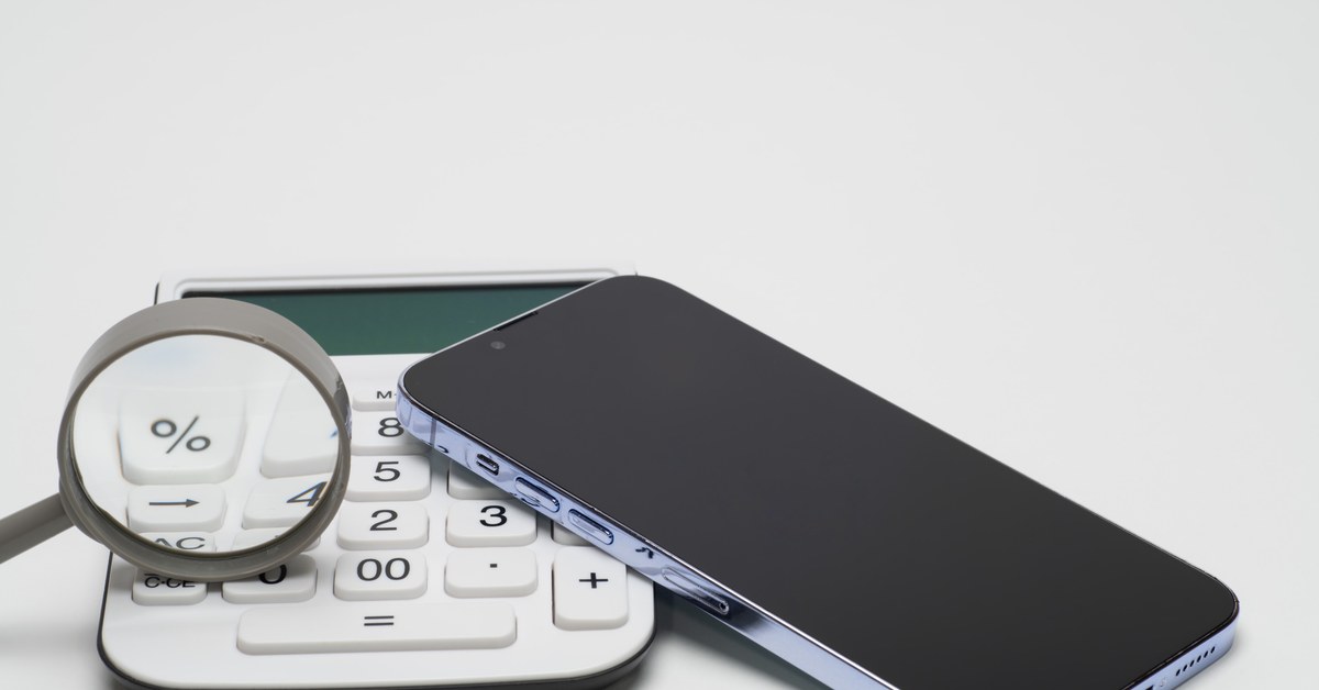 スマートフォンと電卓、虫眼鏡を並べて料金を確認する様子